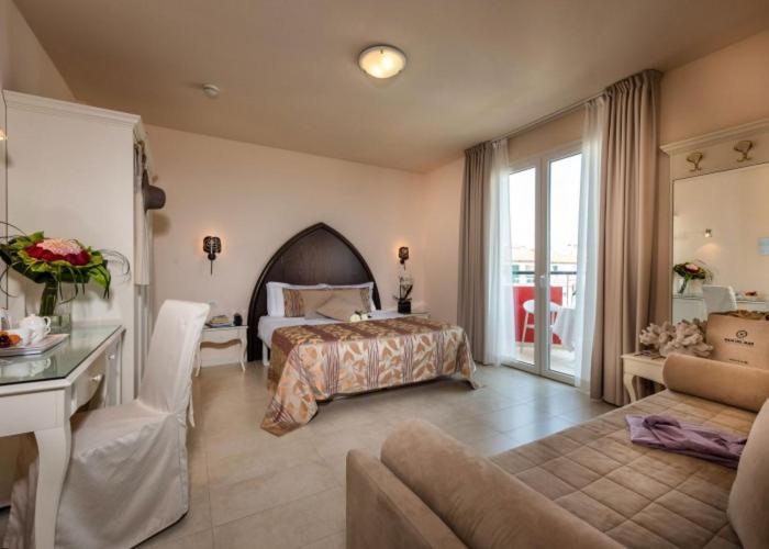 een slaapkamer met een bed en een woonkamer bij Baia del Mar Beach Boutique Hotel in Lido di Jesolo