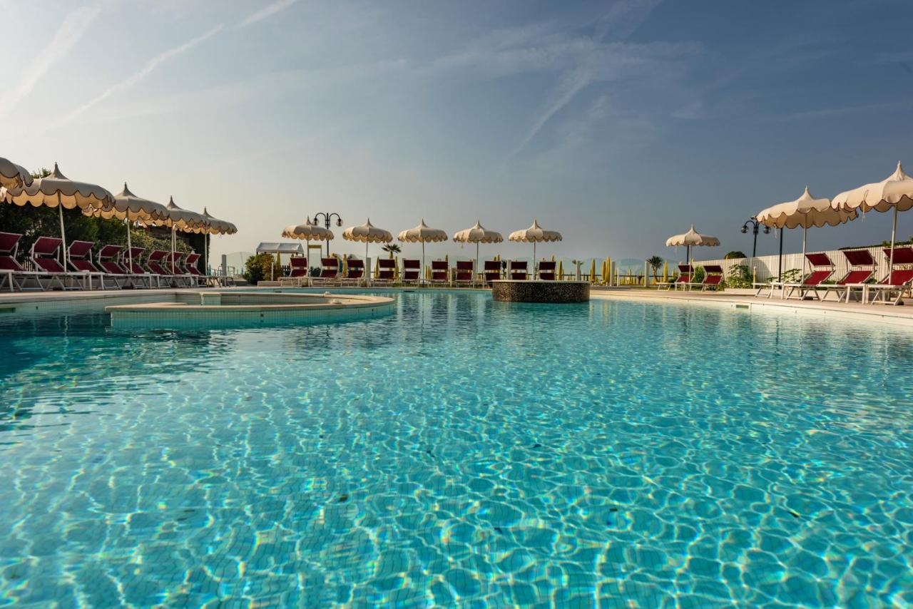 een groot zwembad met ligstoelen en parasols bij Baia del Mar Beach Boutique Hotel in Lido di Jesolo