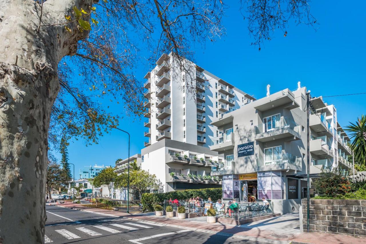 een wit gebouw aan een straat met een boom bij Apartamentos Turisticos Paraiso in Funchal