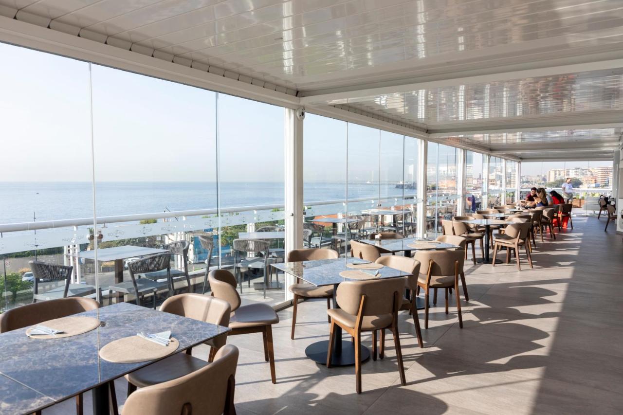 een restaurant met tafels en stoelen en uitzicht op de oceaan bij Plaza Hotel Catania in Catania