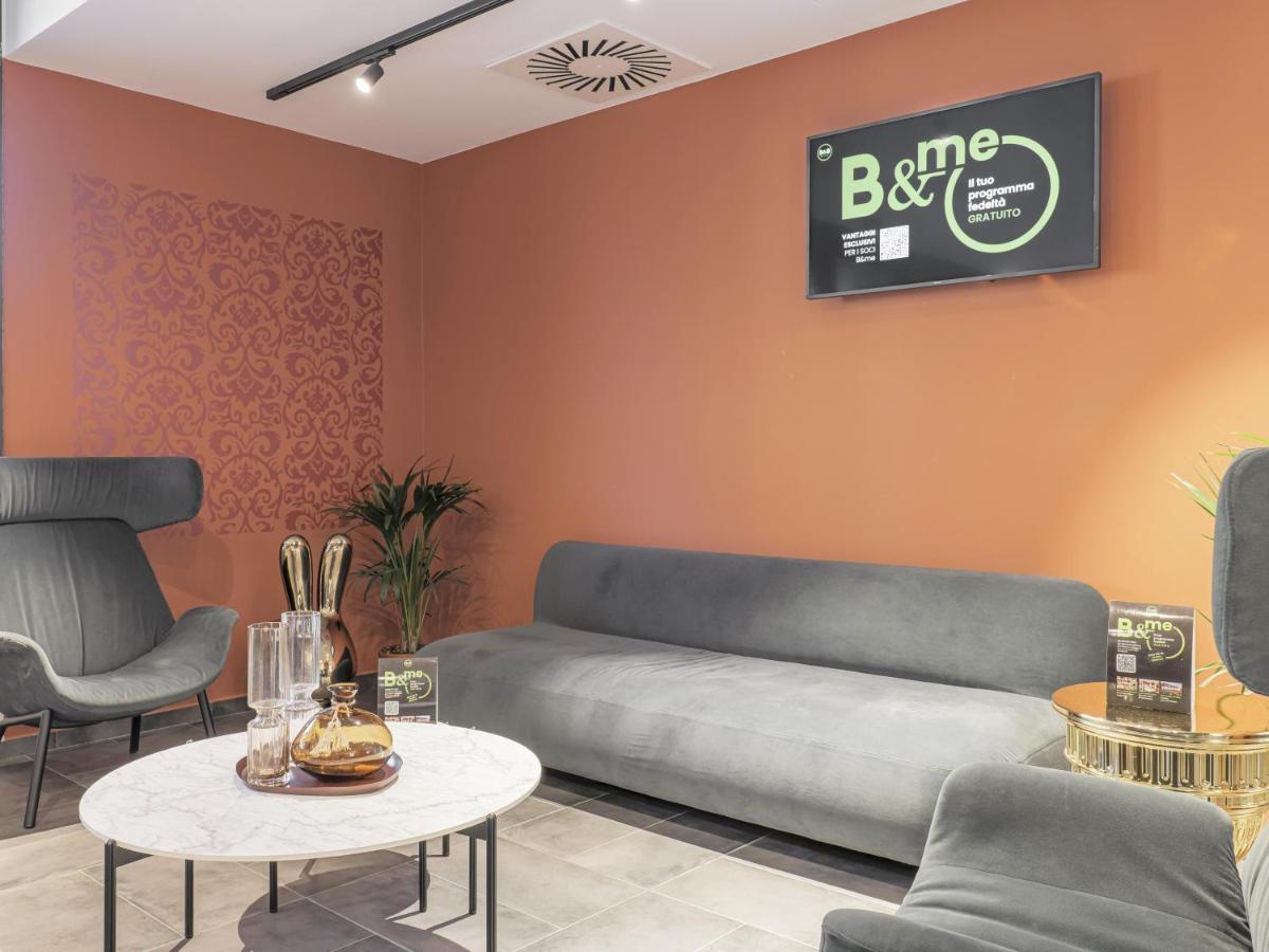 een woonkamer met een bank, stoelen en een tafel bij B&B HOTEL Prato City Center in Prato