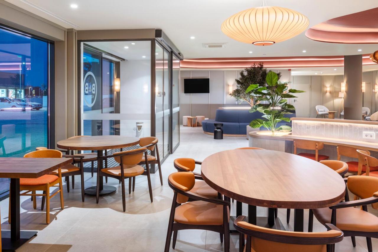 een restaurant met tafels, stoelen en een bank bij B&B HOTEL Vila do Conde in Vila do Conde