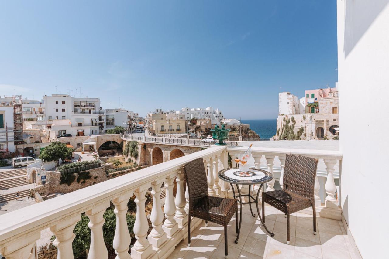 een balkon met een tafel en stoelen en uitzicht op de stad bij Lamare cucina e dimore in Polignano a Mare