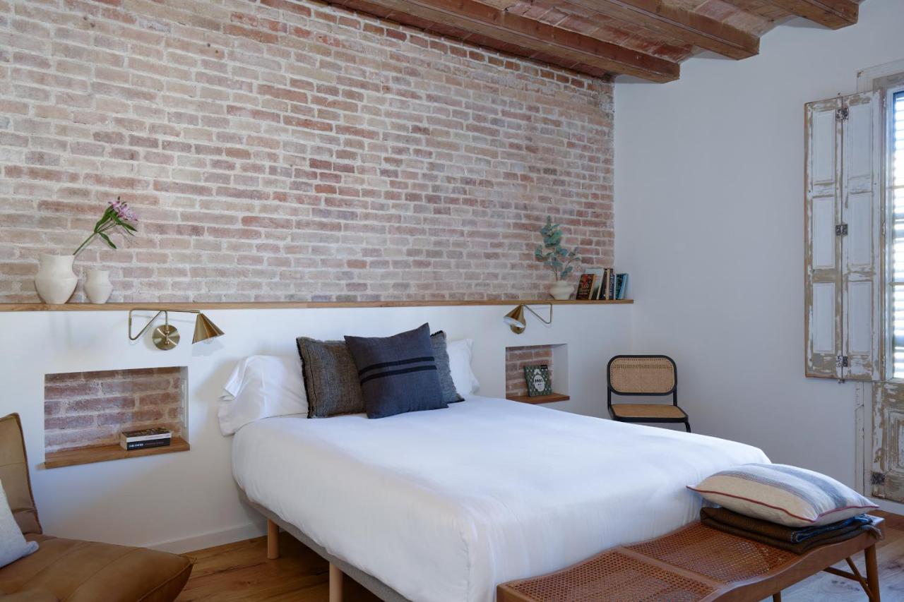 een slaapkamer met een wit bed en een bakstenen muur bij Factory Apartments Barcelona in Barcelona