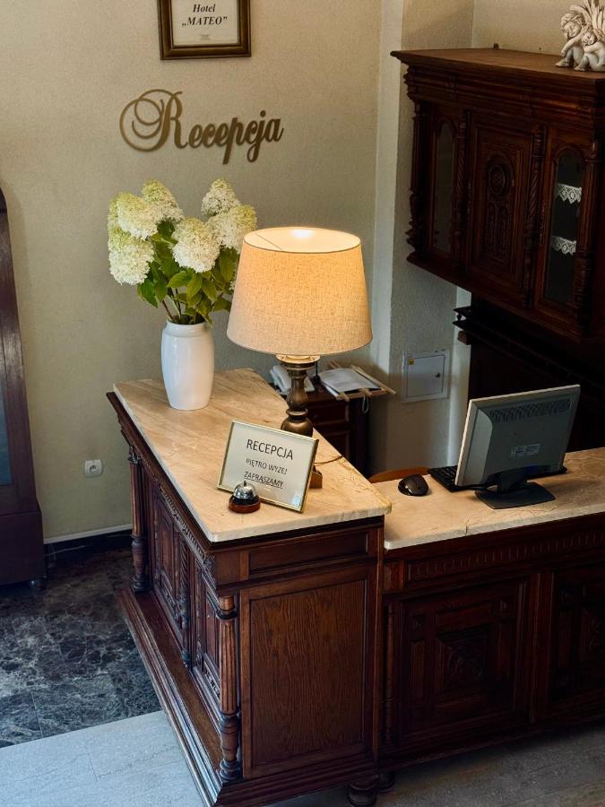 een bureau met een lamp en bloemen erop bij Hotel Mateo in Stopnica