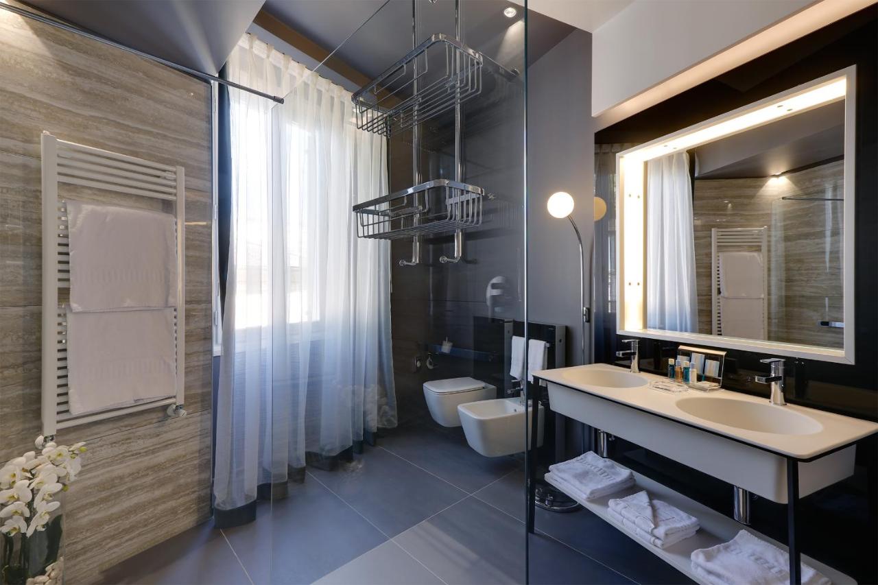 een badkamer met een wastafel, een toilet en een spiegel bij Stendhal Luxury Suites in Rome