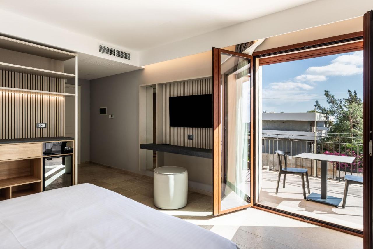 een slaapkamer met een balkon, een bed en een tv. bij Hotel Netum Mare in Noto Marina