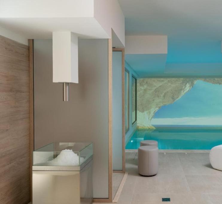 een badkamer met een glazen kast en een slaapkamer bij Margaida Boutique Hotel & SPA in Cala Gonone