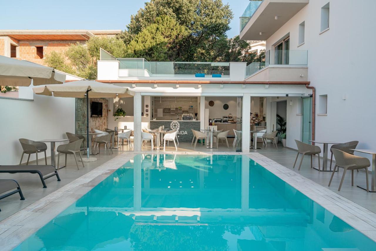 een buitenterras met een zwembad, tafels en stoelen bij Margaida Boutique Hotel & SPA in Cala Gonone