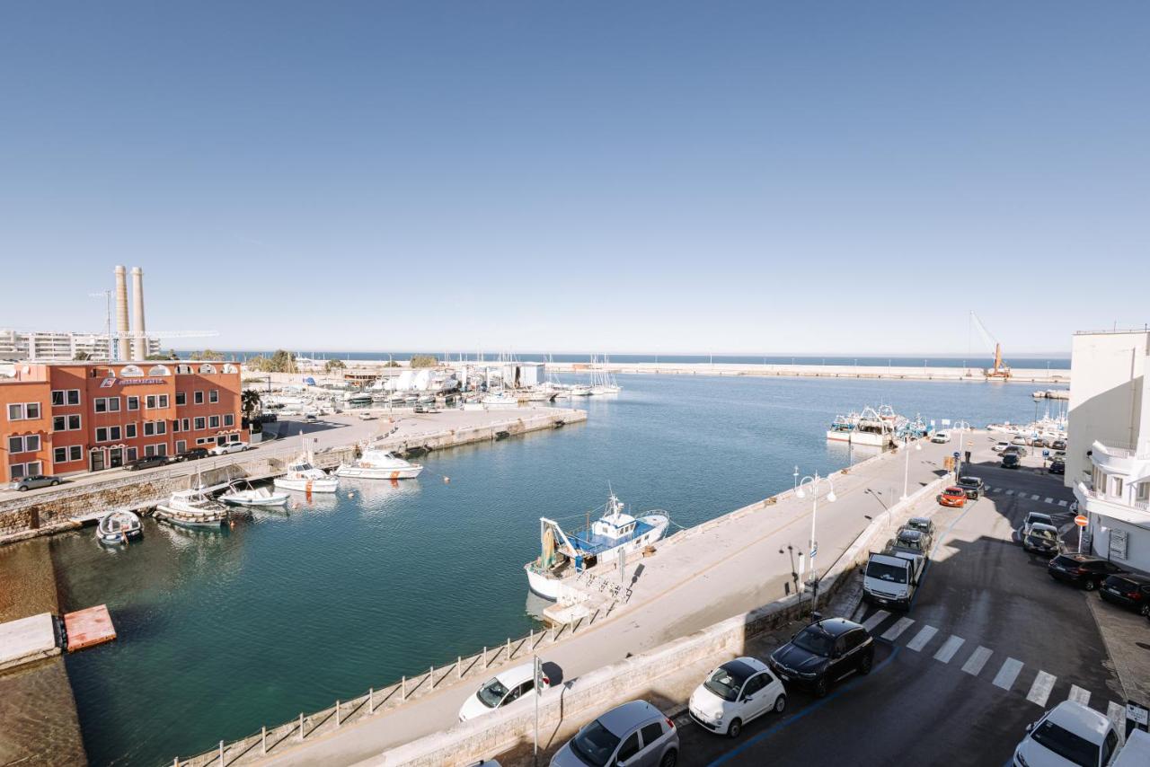 een jachthaven met auto's en een boot in het water bij Palazzo Giuditta in Monopoli