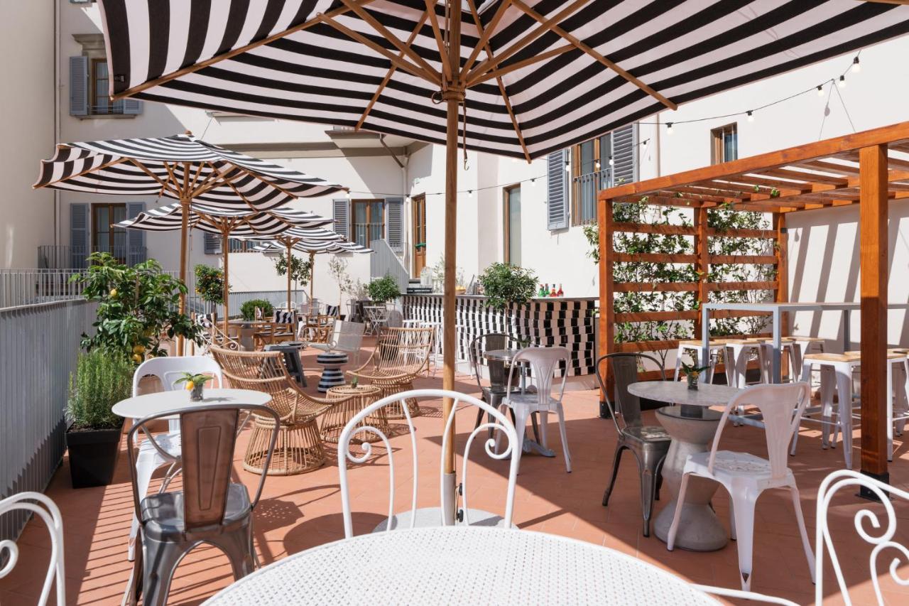 een terras buiten met tafels, stoelen en parasols bij Ruby Bea Hotel Florence in Florence
