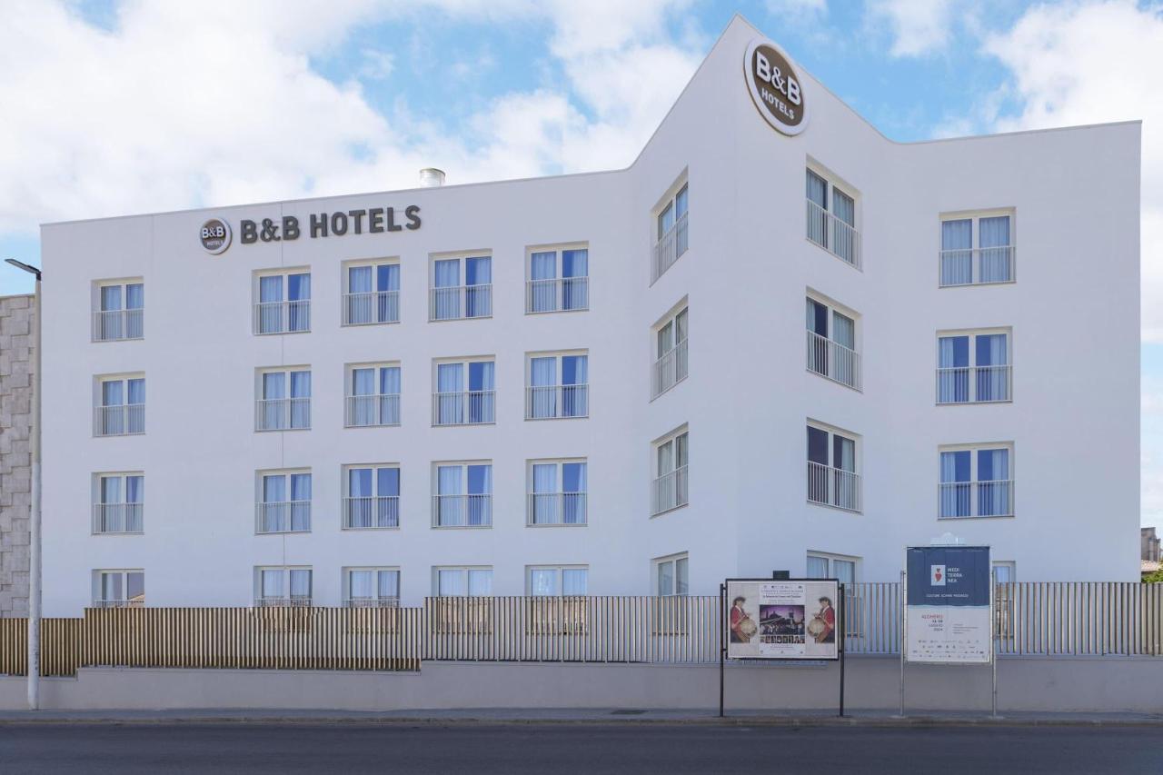 een groot wit gebouw met een uithangbord erop bij B&B HOTEL Sassari in Sassari