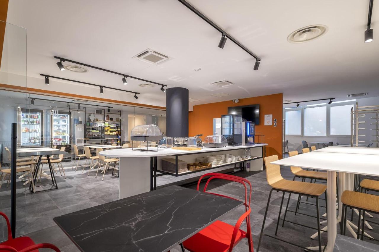 een restaurant met witte tafels en stoelen en ramen bij B&B HOTEL Sassari in Sassari