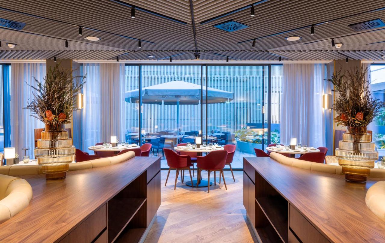 een restaurant met tafels en stoelen en grote ramen bij Altis Porto Hotel, a member of Preferred Hotels & Resorts- LVX i