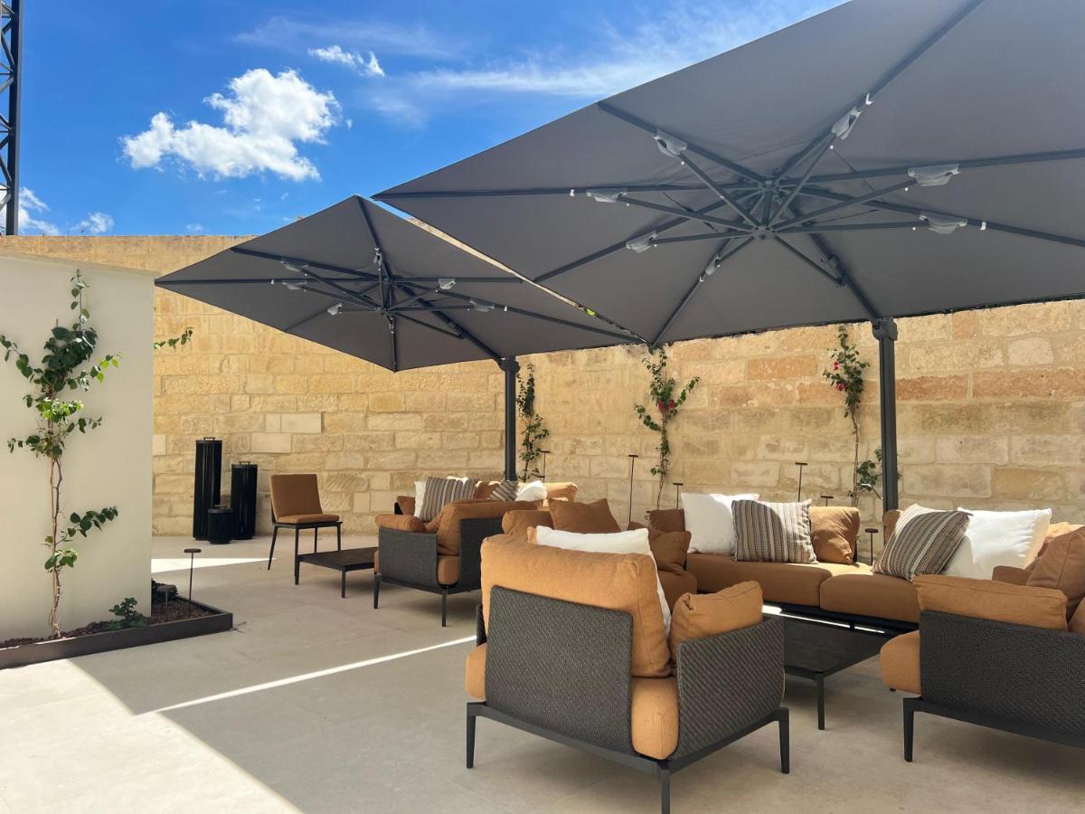 een terras met banken en stoelen onder een grote parasol bij Palazzo Giusti Lecce - Exclusive Boutique hotel in Lecce