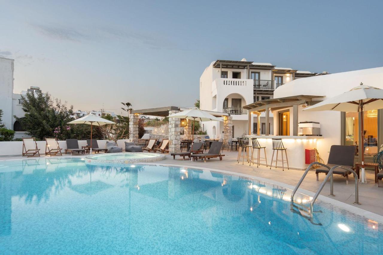 een zwembad met ligstoelen en parasols naast een gebouw bij Melidron Hotel Suites Villas in Agios Prokopios