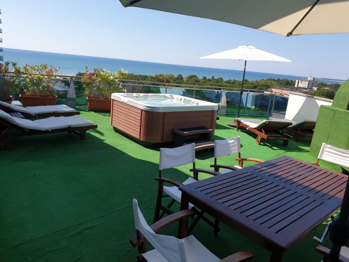 een terras met een bubbelbad en een tafel en stoelen bij Hotel Cristallo in Lignano Sabbiadoro