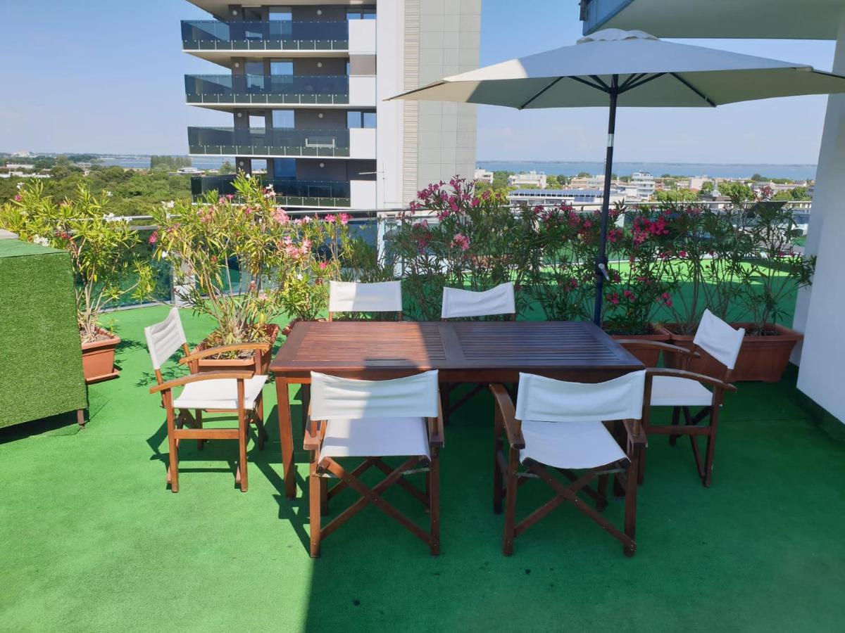 een houten tafel en stoelen met een parasol op een balkon bij Hotel Cristallo in Lignano Sabbiadoro