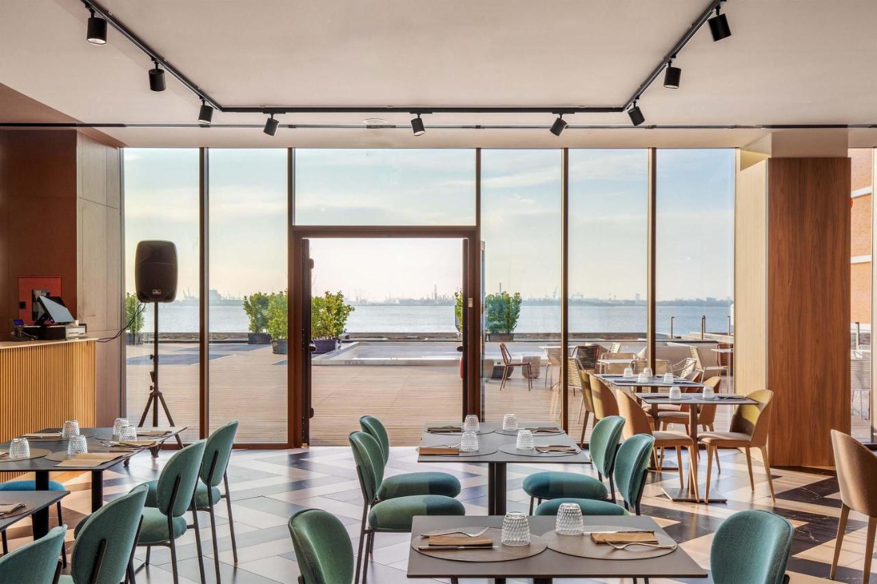 een restaurant met tafels en stoelen en uitzicht op de oceaan bij B&B HOTEL Venezia Laguna in Venetië