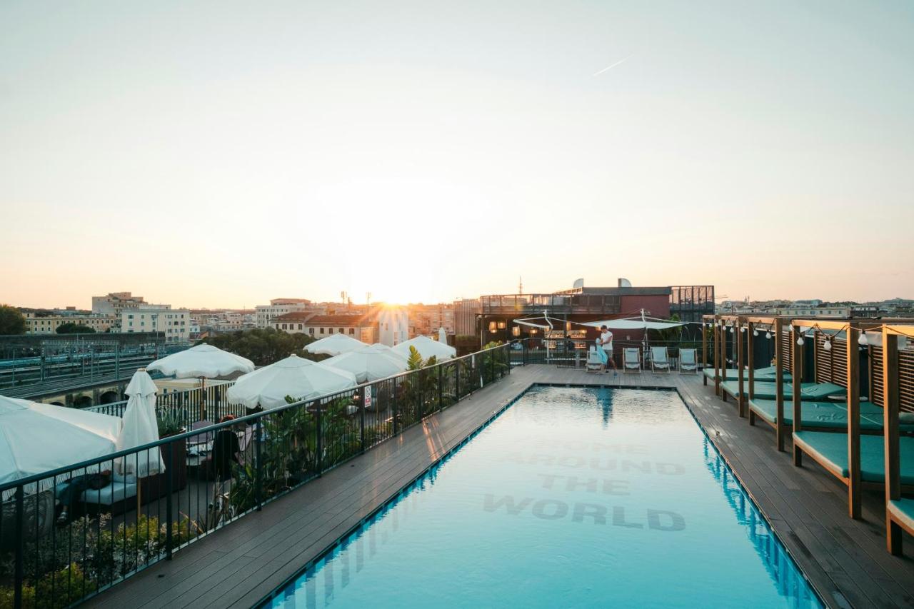 een zwembad op het dak van een gebouw met de zonsondergang bij The Social Hub Rome in Rome
