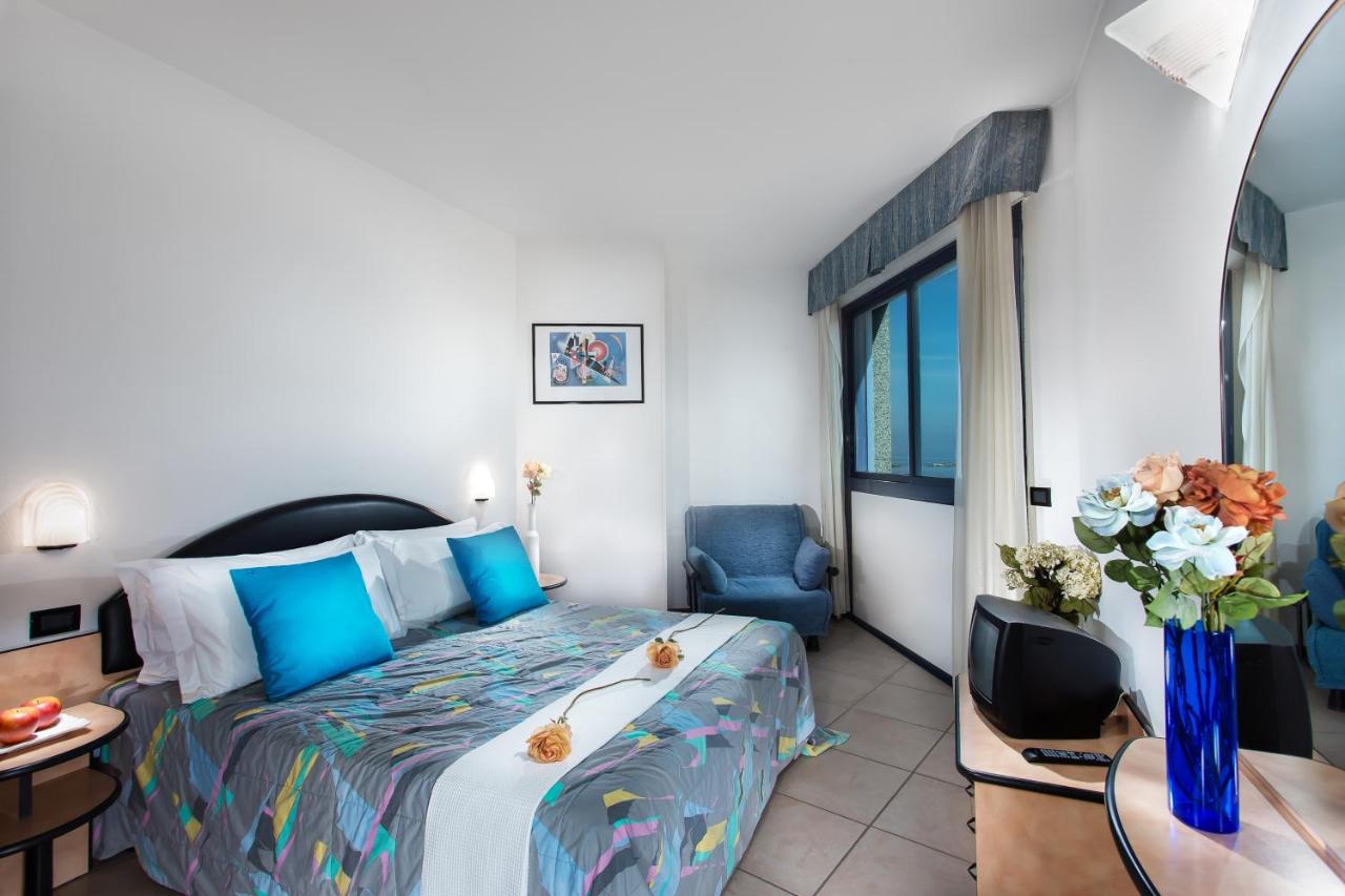 een slaapkamer met een bed, een tafel en stoelen bij Lido Hotel Residence in Cesenatico