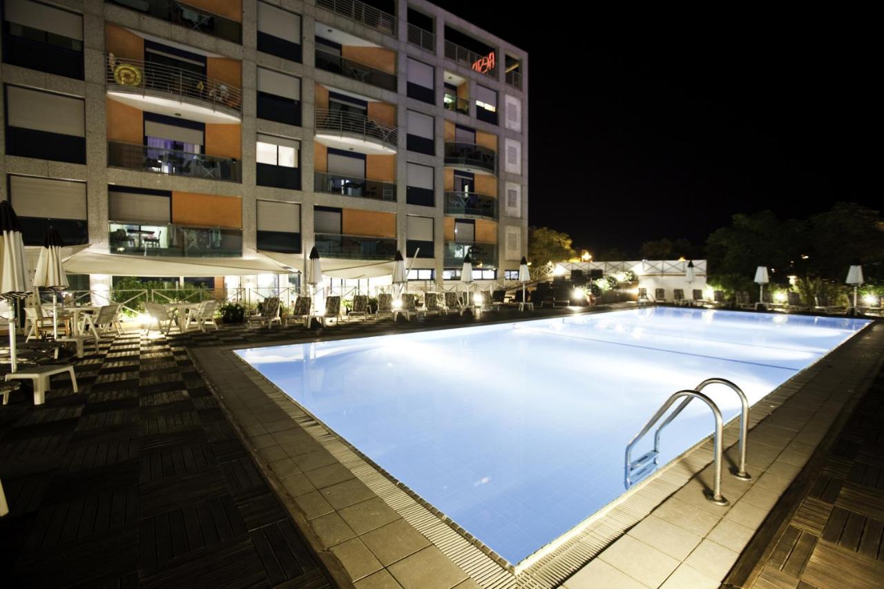 een groot zwembad voor een gebouw 's nachts bij Lido Hotel Residence in Cesenatico