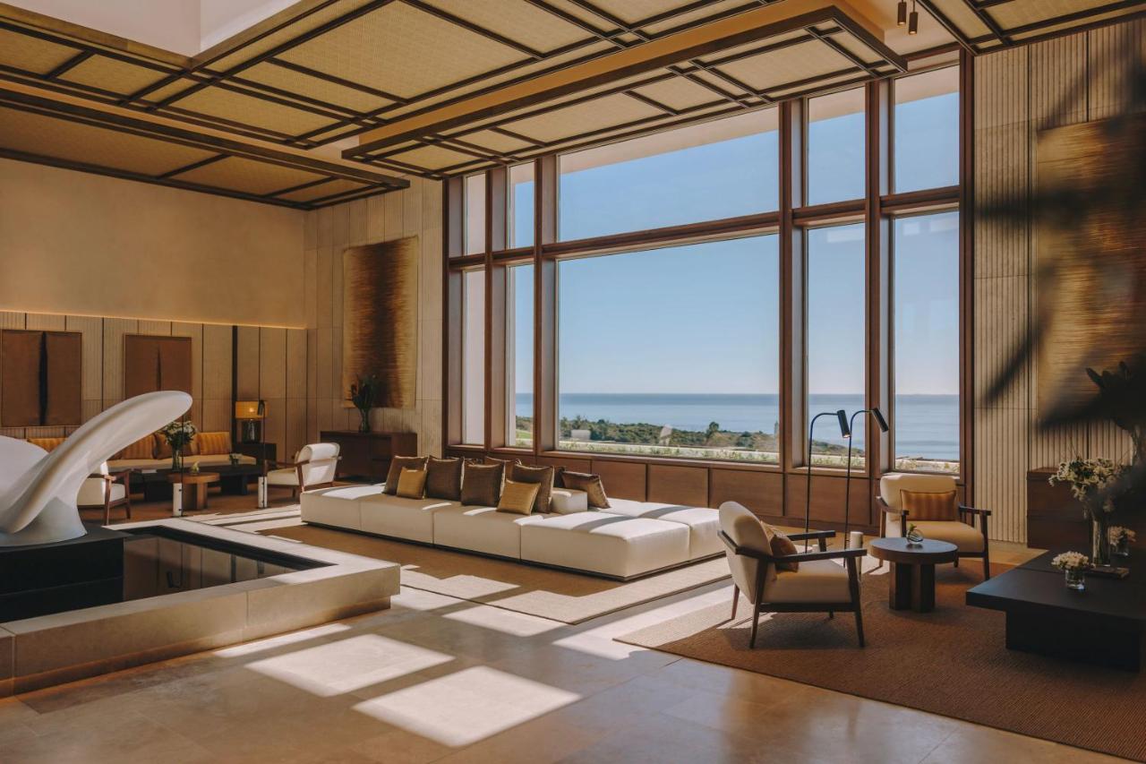 een woonkamer met een bank en een groot raam bij Fairmont La Hacienda Costa del Sol in Alcaidesa