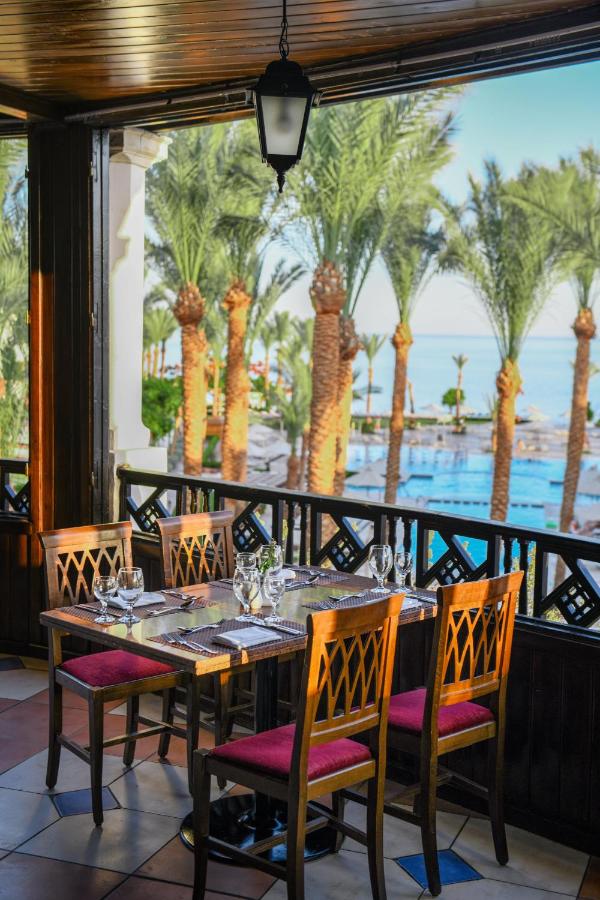 een eetkamer met een tafel en stoelen en palmbomen bij JAZ Fanara Resort in Sharm El Sheikh