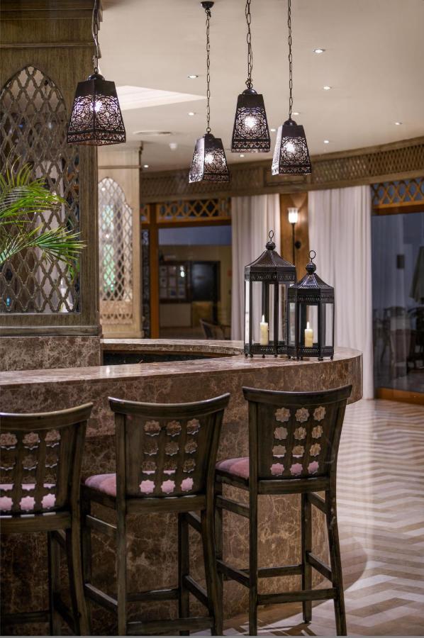 een keuken met een bar met drie stoelen en hanglampen bij JAZ Fanara Resort in Sharm El Sheikh