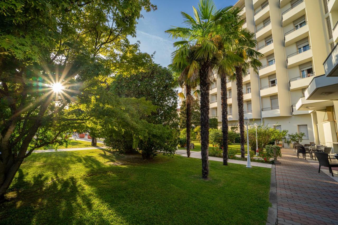 een park voor een gebouw met palmbomen bij Hotel Ariston Molino Buja in Abano Terme