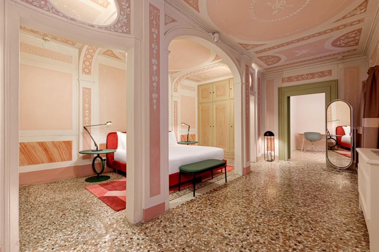 een slaapkamer met een bed en een kamer met een spiegel bij Palazzo Dei Fiori by Room Mate in Venetië