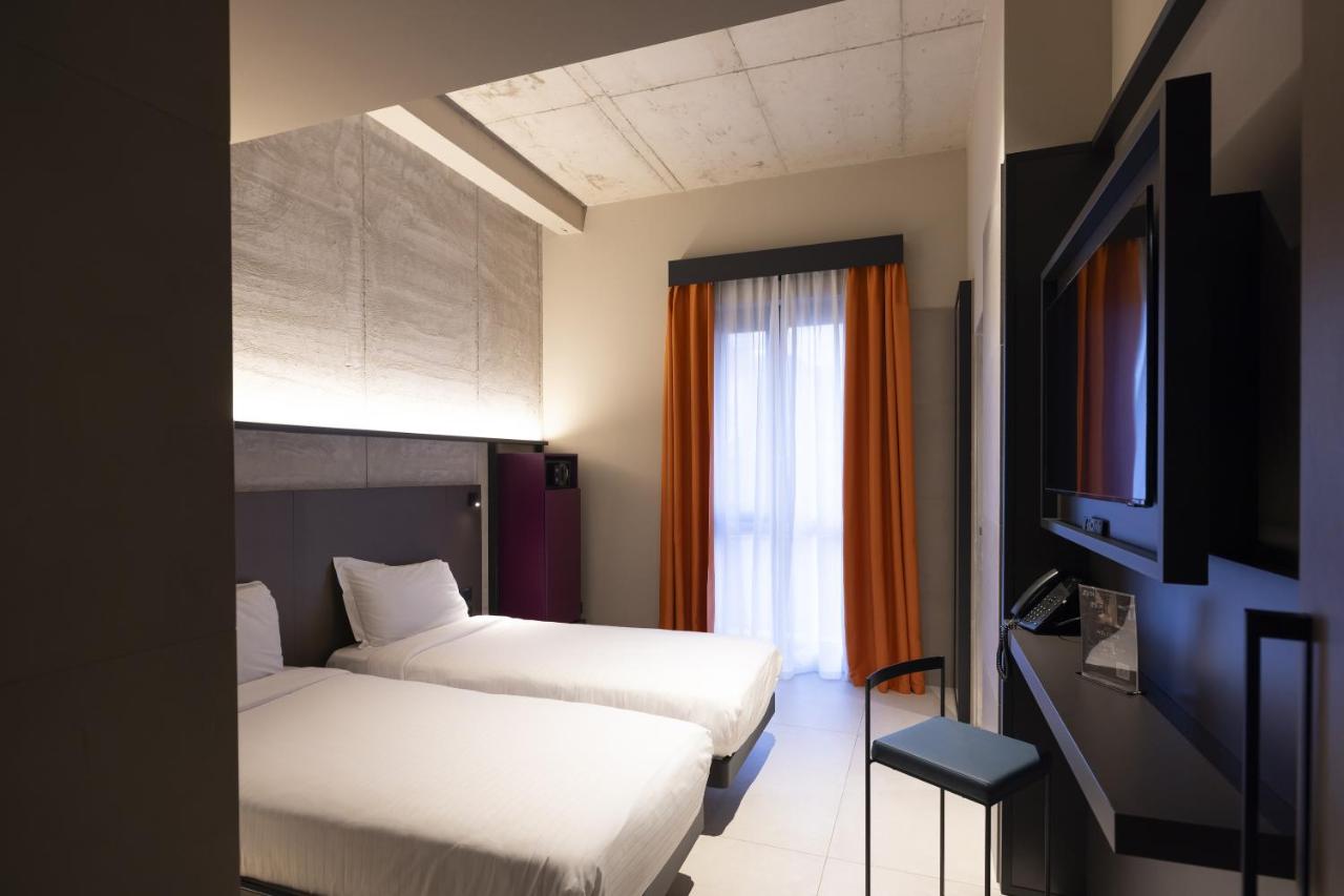 een hotelkamer met twee bedden en een televisie bij Joy 124 Hotel Milano in Milaan