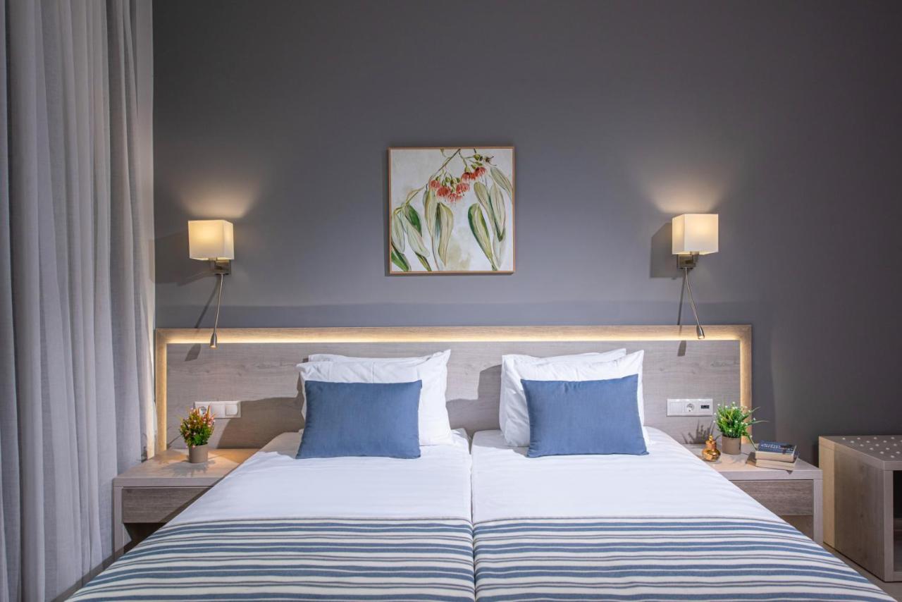 een slaapkamer met een groot bed met twee blauwe kussens bij Saint George Gournes Bay "by Checkin" Adults Only in Gourne