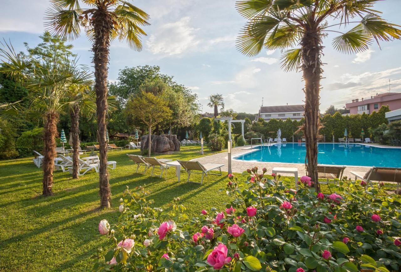 een park met een zwembad, palmbomen en bloemen bij Hotel Harrys' Garden in Abano Terme