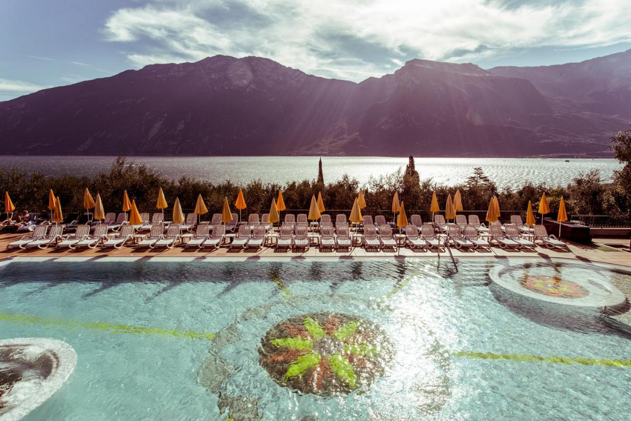 een zwembad met ligstoelen en een waterpartij bij Hotel Ilma Lake Garda Resort in Limone sul Garda