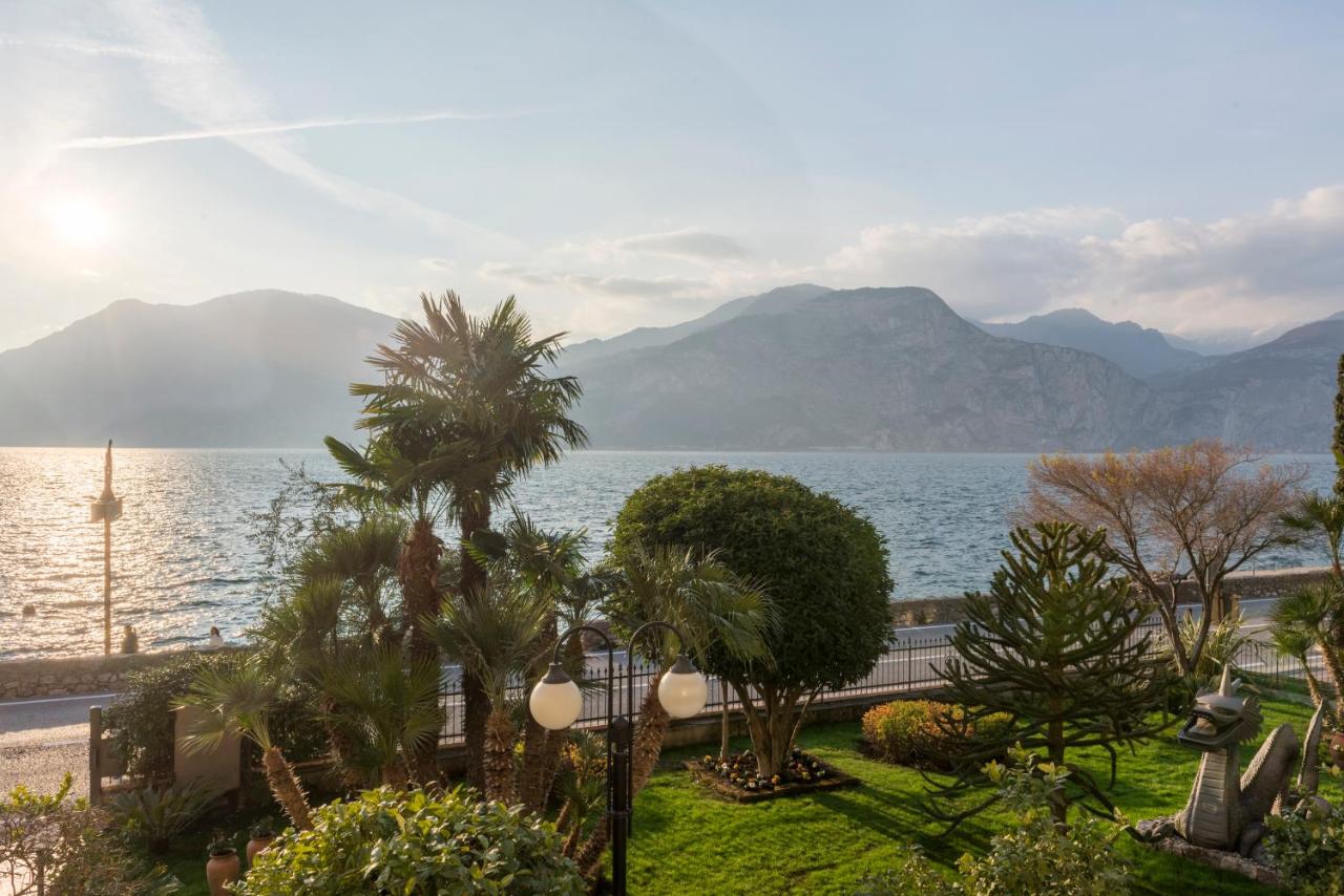 een uitzicht op een wateroppervlak met bomen en bergen bij Hotel Drago by Double Hospitality in Brenzone sul Garda
