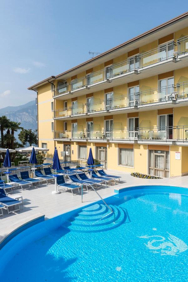 een hotel met een zwembad en ligstoelen en een gebouw bij Hotel Drago by Double Hospitality in Brenzone sul Garda