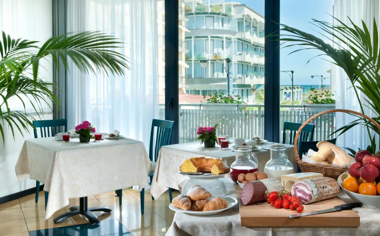 een tafel met eten erop in een kamer met ramen bij Hotel Gabbiano in Cattolica
