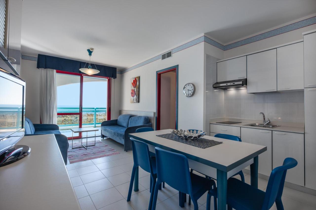 een keuken en woonkamer met een tafel en stoelen bij Aparthotel Imperial in Bibione