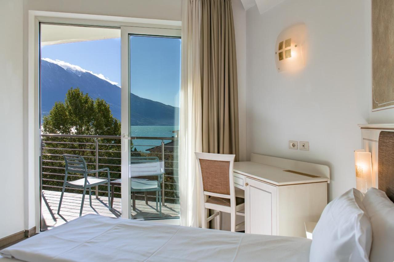 een slaapkamer met een bed en een balkon met uitzicht bij Hotel Sogno del Benaco in Limone sul Garda