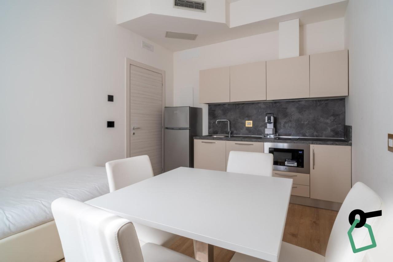 een witte keuken met een witte tafel en stoelen bij Hotiday Castiglioncello Suite in Castiglioncello