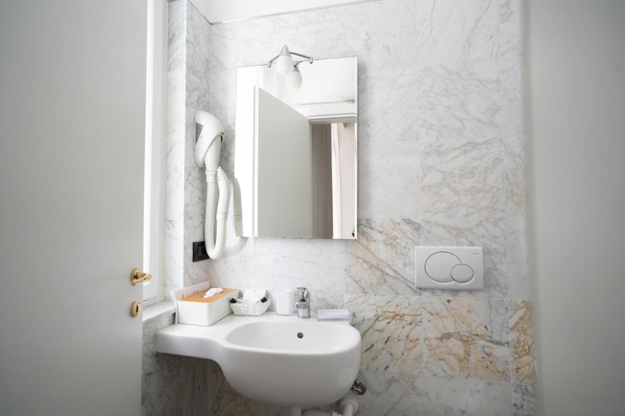 een witte badkamer met een wastafel en een spiegel bij Hotel Excelsior Bay in Malcesine
