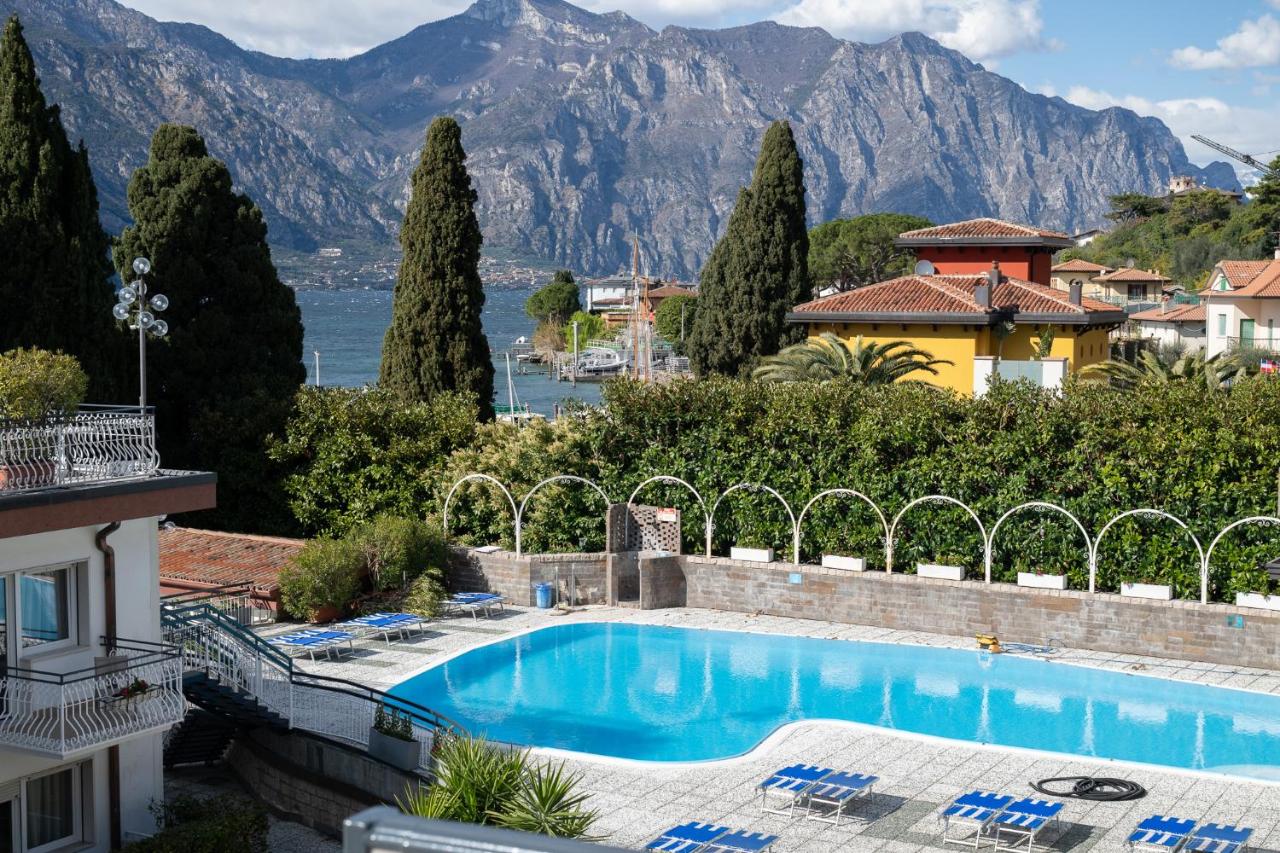 een zwembad bij een villa met bergen op de achtergrond bij Hotel Excelsior Bay in Malcesine