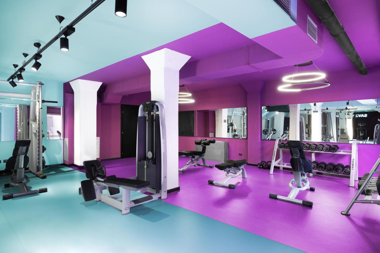 een sportschool met paarse muren en loopbanden bij CX Milan Bicocca in Milaan