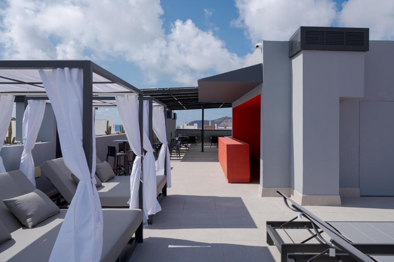 een dakterras met stoelen en gordijnen op een dak bij Hotel LIVVO La Escarlata in Las Palmas de Gran Canaria