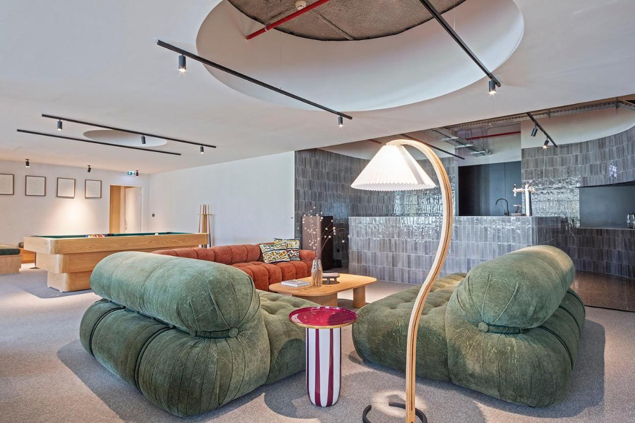een woonkamer met twee groene stoelen en een biljarttafel bij Hotel Acta Moa in Lissabon