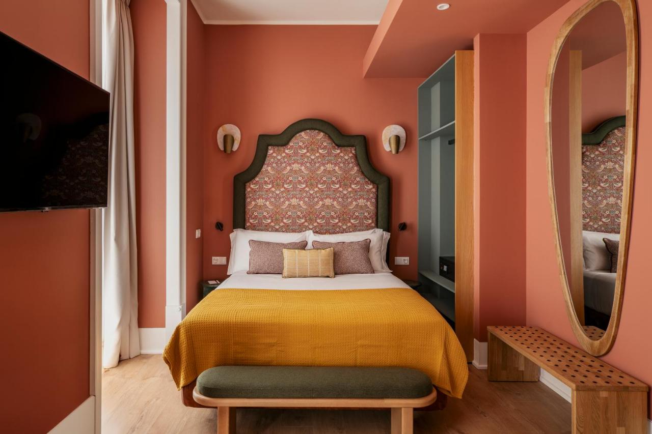een slaapkamer met een bed, oranje muren en een spiegel bij Vincci Baixa Suites Apartments in Lissabon