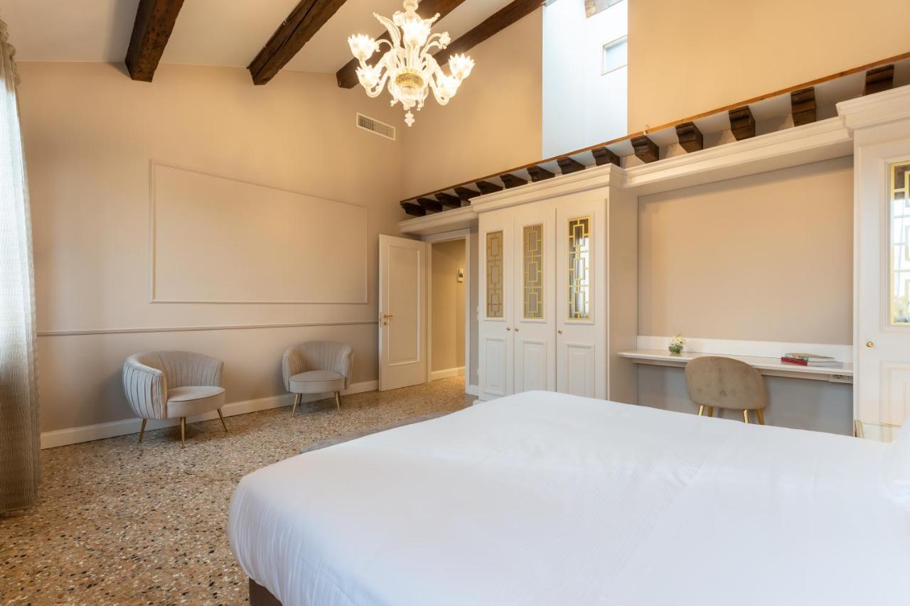 een slaapkamer met een groot wit bed en stoelen bij San Vio Palace Luxury Apartments in Venetië