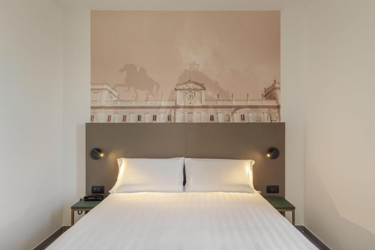 een slaapkamer met een groot wit bed en een muur bij B&B HOTEL Piacenza in Piacenza