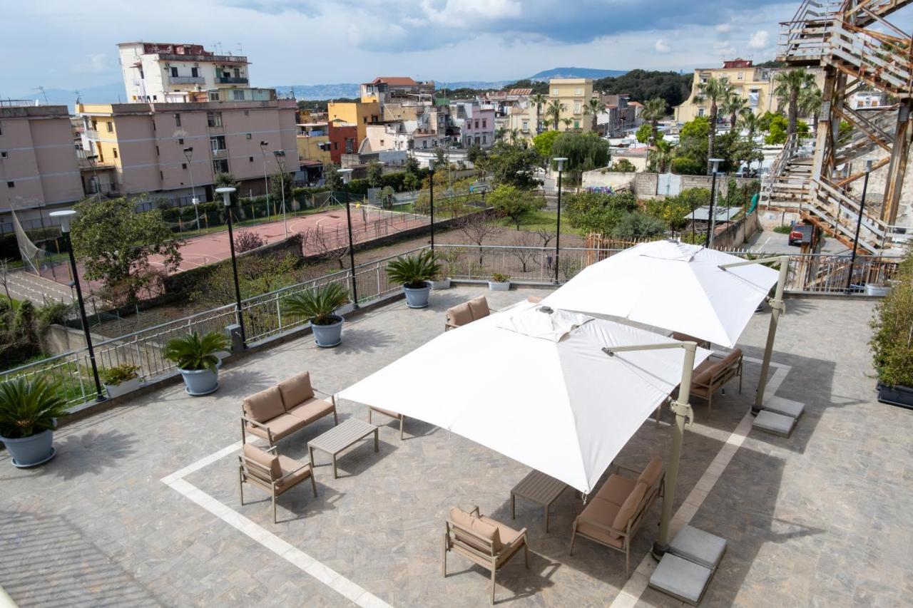 een terras met een tafel, stoelen en parasols bij Palazzo Adele Rooms & Apartments in Ercolano